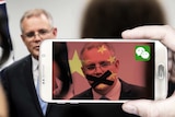 Scott Morrison viewed through a mobile phone coloured with the colours of the Chinese flag.