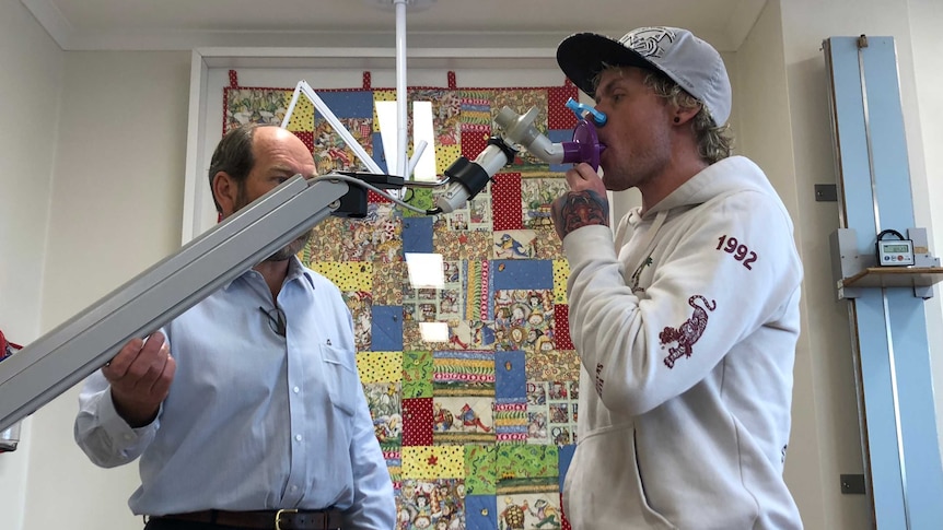 A man breathes into a machine while visiting the doctor