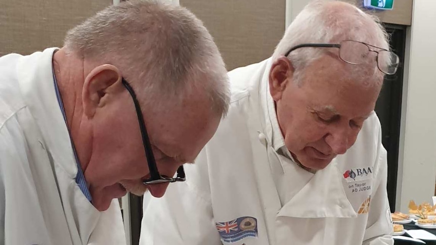 Two men judge the quality of pies in a competition