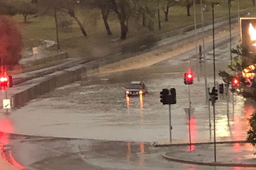 A car in floodwaters at an intersection.