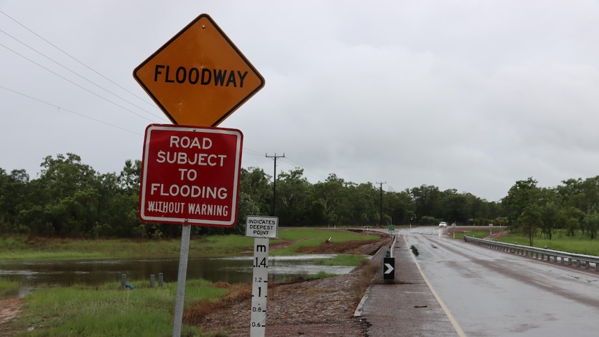 A sign warning of flooding on a road in Darwin, on a grey and rainy day. 