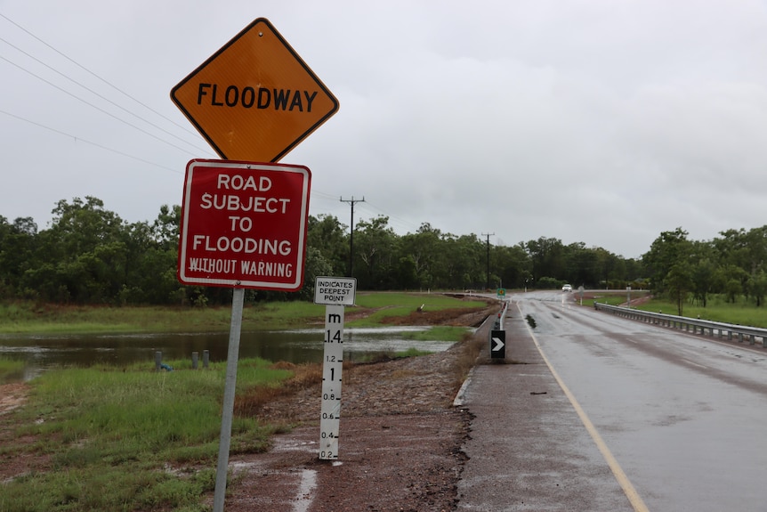 A flood warning sign on a road in Darwin on a gray and rainy day. 