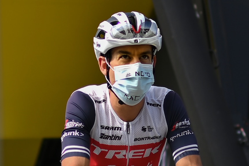 A man sitting on a bike with a mask saying No to Racism