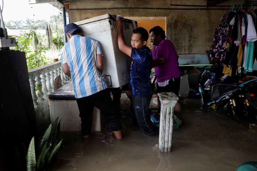 People are moving a fridge during a flood.