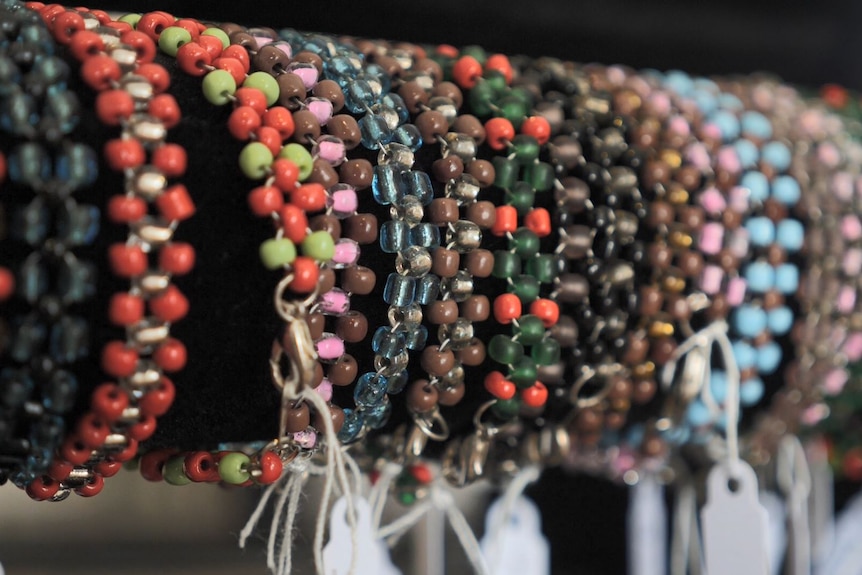 A group of beaded, colourful bracelets are displayed on a rack.
