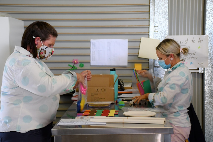 Two ladies put craft supplies into bags.