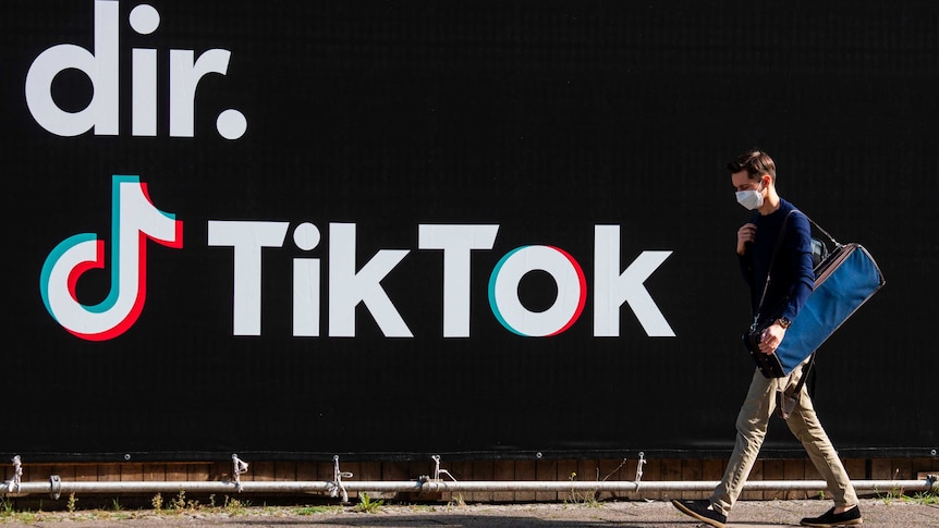 A man works in front of a black wall that says TikTok on it.