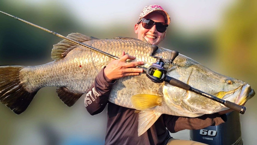 A darwin fisho holds a huge barramundi