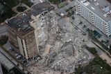 Search and rescue personnel work in the rubble of the 12-story condo tower that crumbled to the ground.