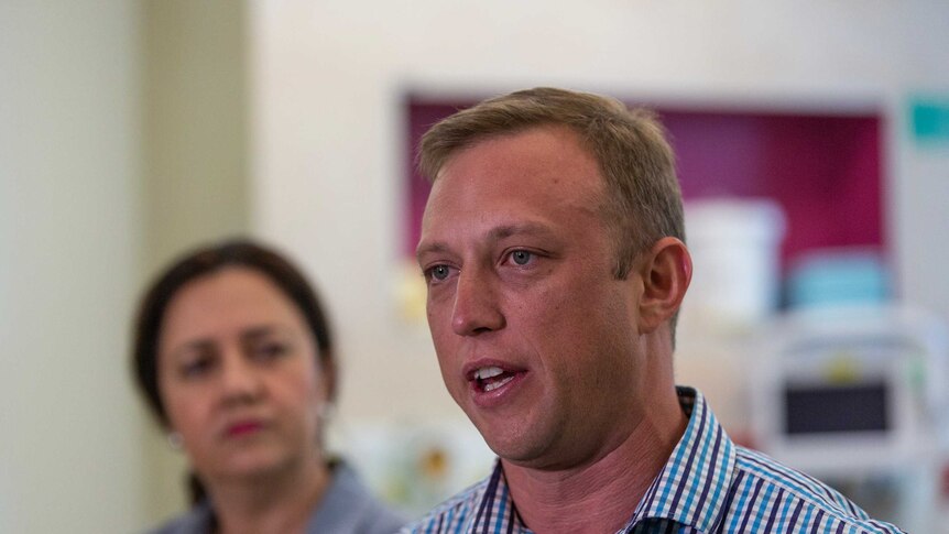 MP Steven Miles, with Premier Annastacia Palaszczuk in background, speaks to media in Brisbane.