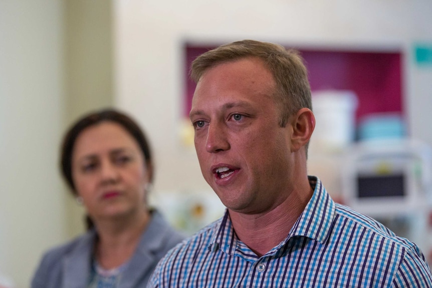 MP Steven Miles, with Premier Annastacia Palaszczuk in background, speaks to media in Brisbane.