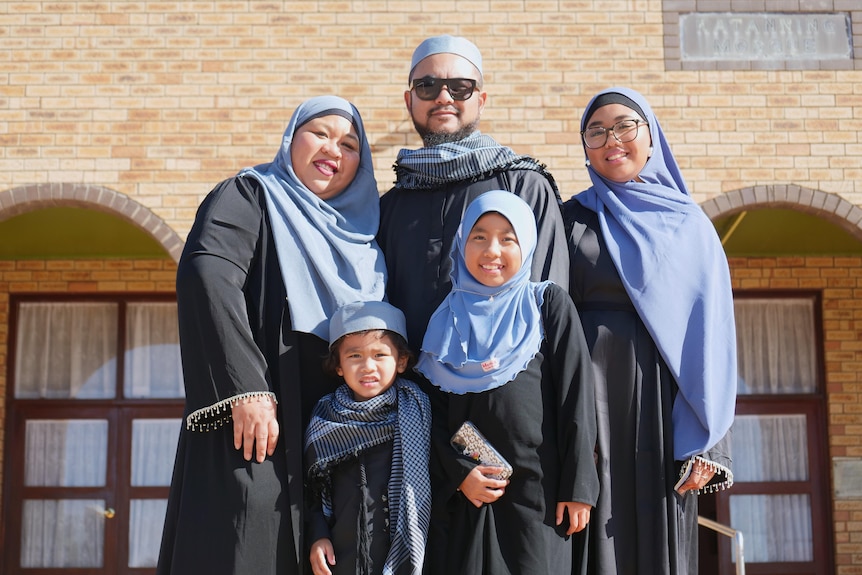 Muslim family stand outside a Mosque.