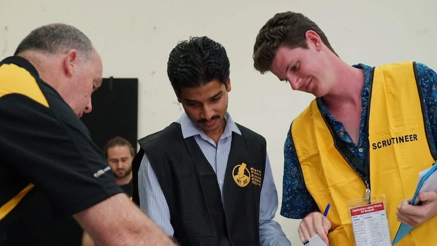 An NTEC employee and scrutineer count votes in the NT election.