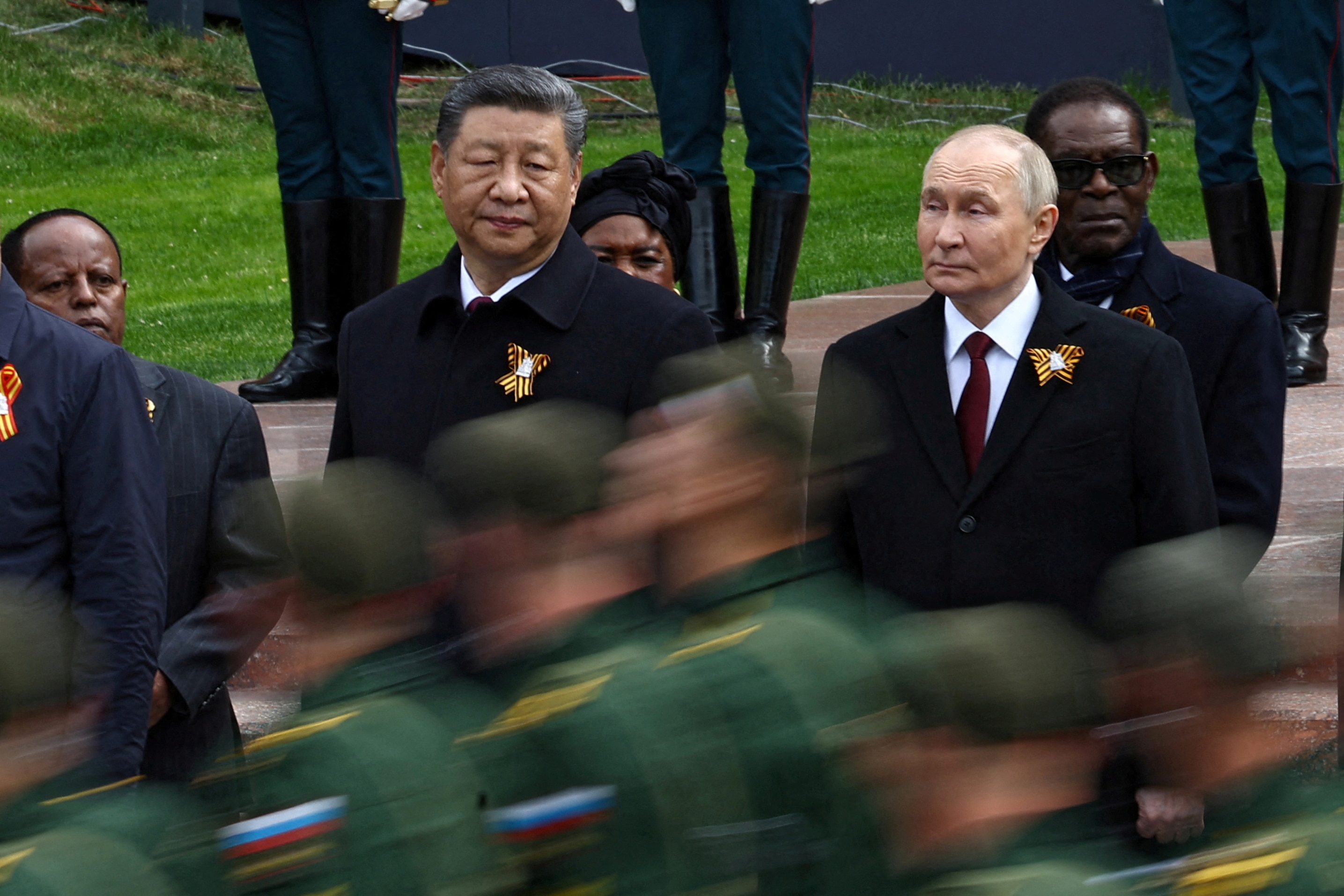 Xi Jinping and Vladimir Putin stand side by side, watching a blur of soldiers march past.