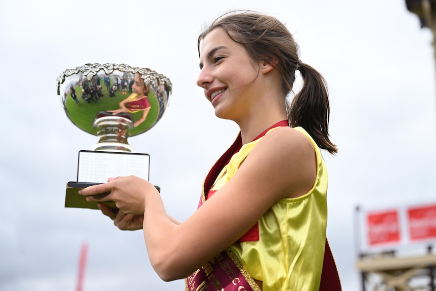 A teenage girl holding up a trophy 