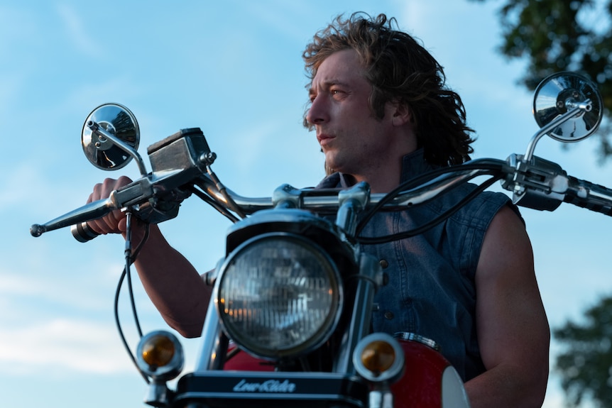 A film still of Jeremy Allen White on an old-fashioned motorbike. He has shoulder-length hair and is looking into the distance.