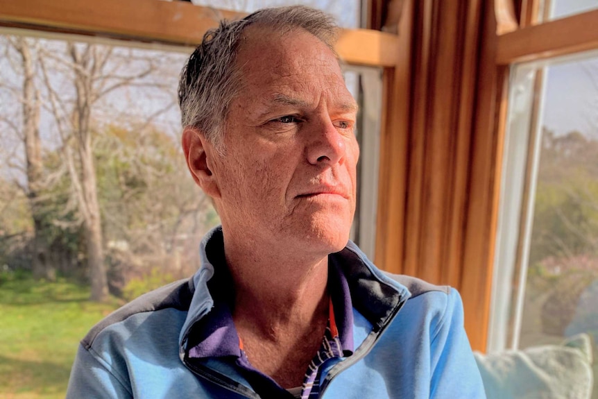 A man in a blue shirt holds a cup of coffee.