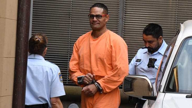 A big man in an orange prison uniform.