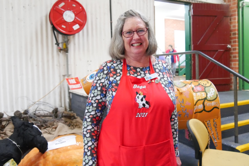 A woman in a red apron smiling.