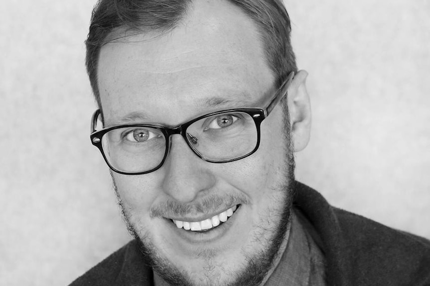 Black and white head shot of a man with glasses.