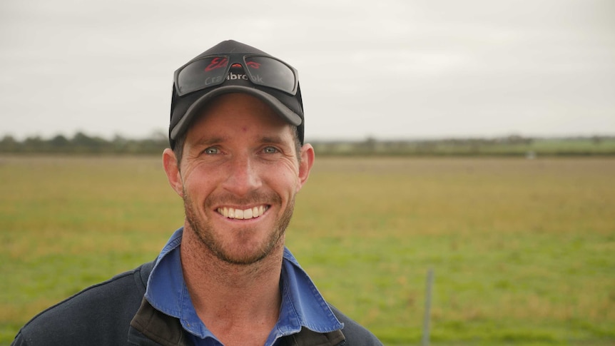 Cranbrook farmer, Sam Lehmann stands in front of a paddock being grazed by sheep.