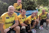 A group of cyclists wearing yellow jerseys crouching on the ground.