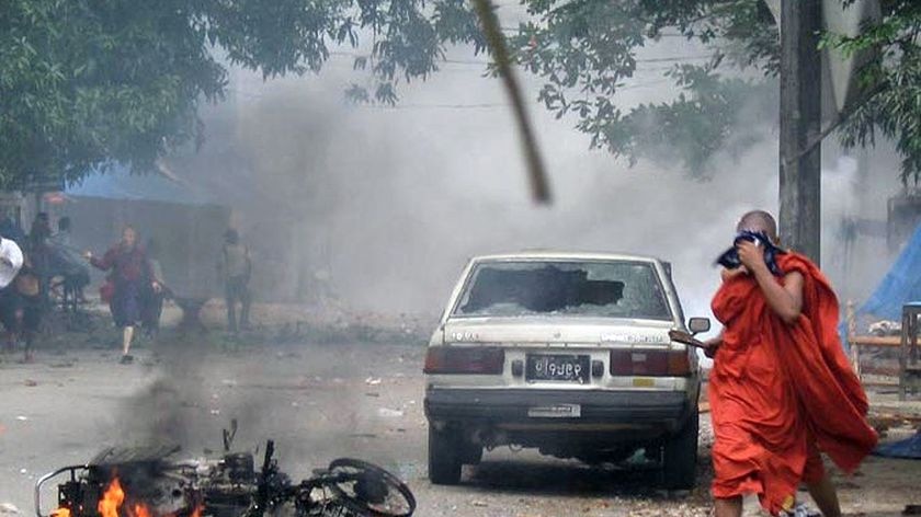 Clashes: A monk runs as tear gas fills the air in downtown Rangoon