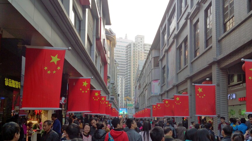 Busy pedestarianed street scene in mainland China with Chinese flags