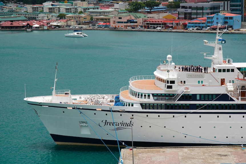 A large white cruise ship docked in the water at St Lucia.