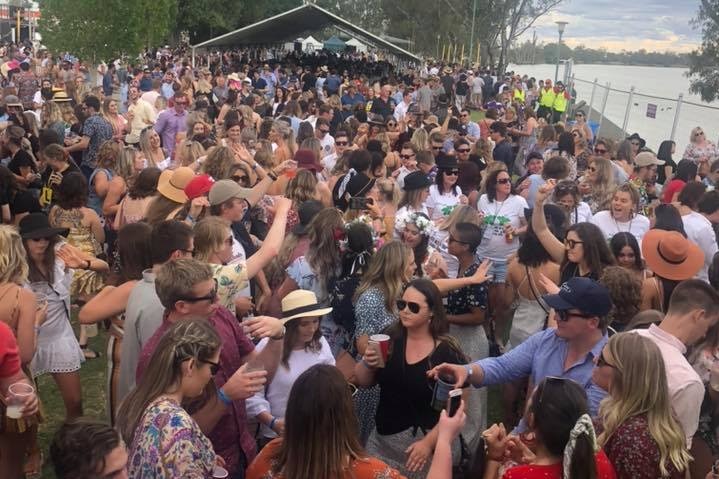 A lawned riverfront full of people.