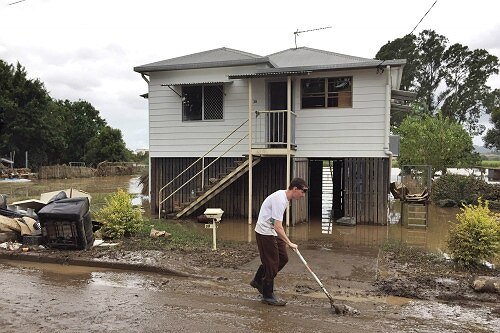 Jared Wyborn shovels mud from the front of his home on Railway St, Murwillumbah.