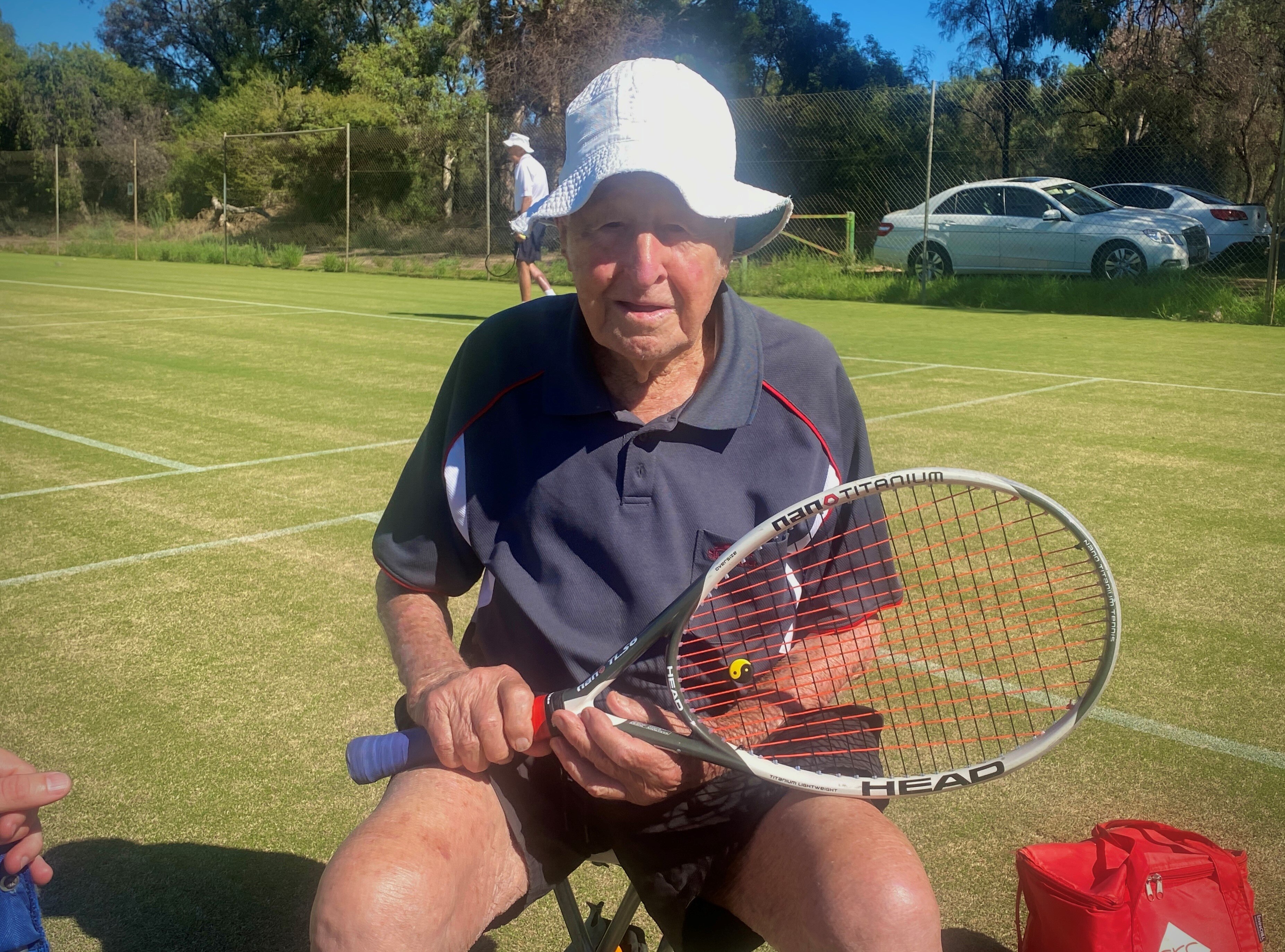 elderly man sitting down holding tennis racquet