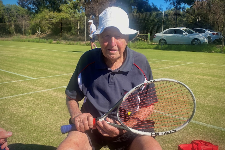 elderly man sitting down holding tennis racquet