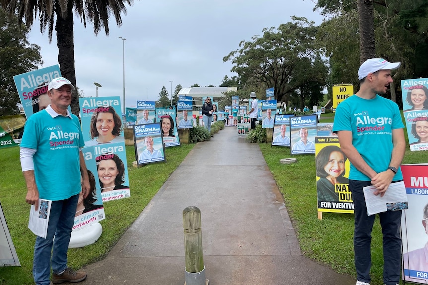 people standing outdoors handing out election campaign material 