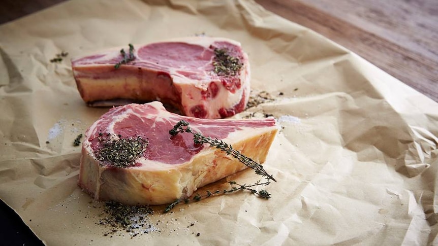 Two fresh beef steaks on the bone with pepper and herbs