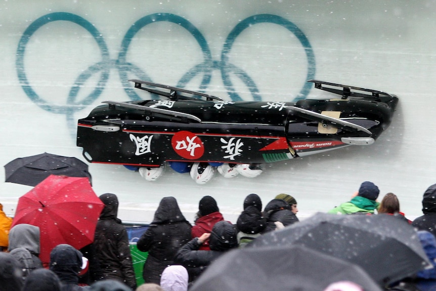 A black, four-man bobsleigh with Japanese characters on the side, is shown upside down