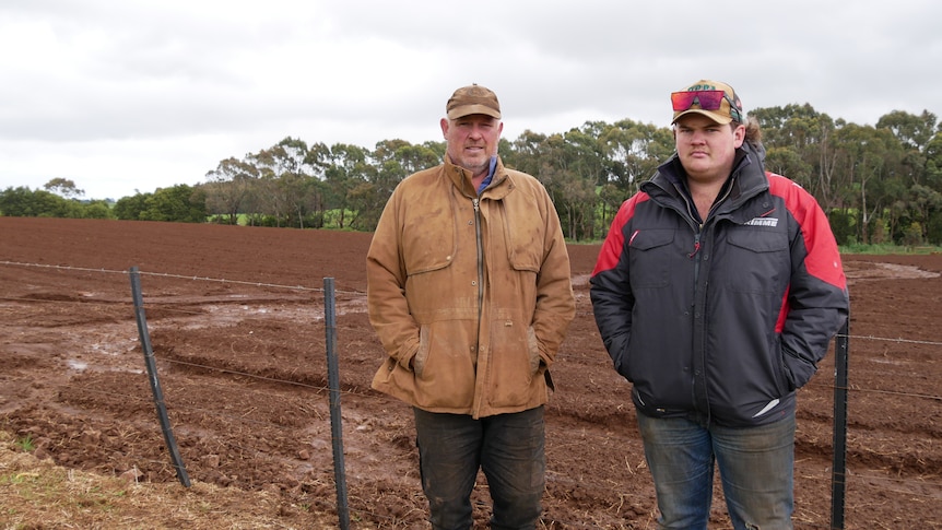 Two men standing in front of a muddy paddock