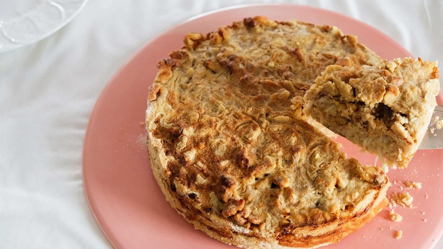 A Bulgarian apple cake on a pink plate with a slice about to be served, an easy and comforting cake recipe.