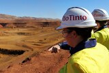 Two people in Rio Tinto hats and high vis vests looking out over West Angelas mine site in the Pilbara
