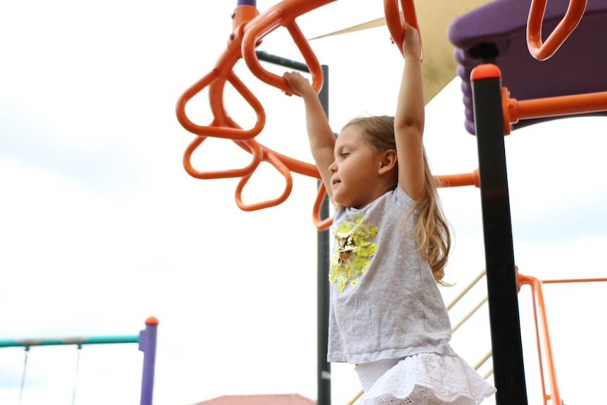 Four year old Eva Garcia swings on the monkey bars