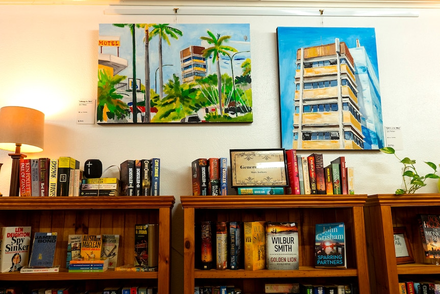 A book shop with two paintings of buildings on the wall.