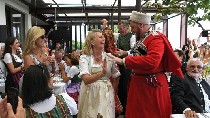 Cossack choir member in traditional uniform speaks with Karin Kneissl at the Austrian Foreign Minister's wedding