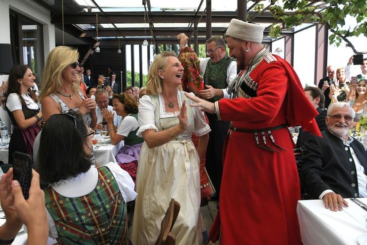 Cossack choir member in traditional uniform speaks with Karin Kneissl at the Austrian Foreign Minister's wedding