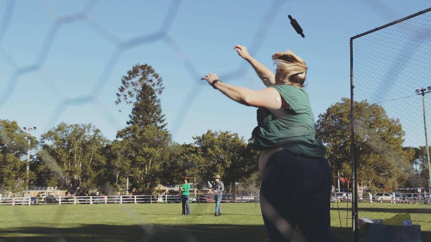 woman throwing rolling pin out onto a grassed oval