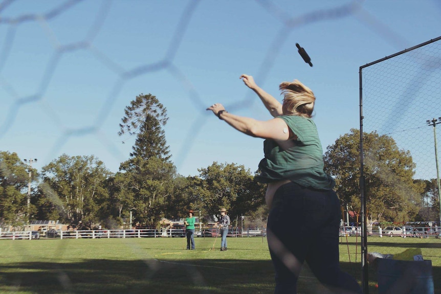 woman throwing rolling pin out onto a grassed oval