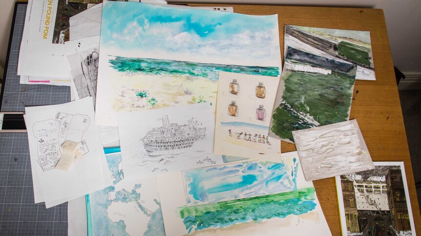 A collection of paper with illustrations on them lie on a table.