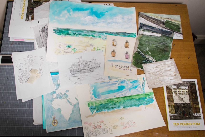 A collection of paper with illustrations on them lie on a table.