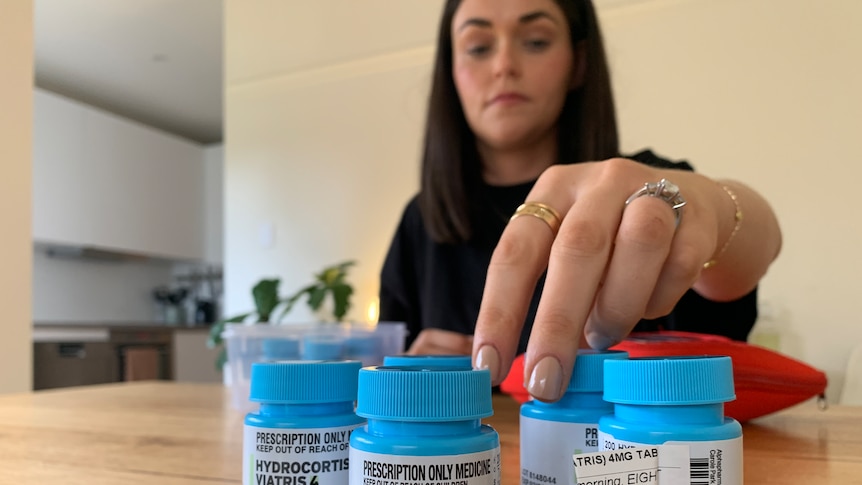 Natalie Sinclair sitting at a table, reaching towards bottles of Hysone and Hydrocortisone.