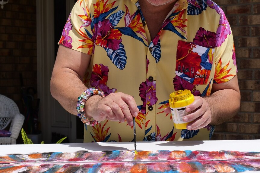 A man in a colourful shirt holding a paintbrush