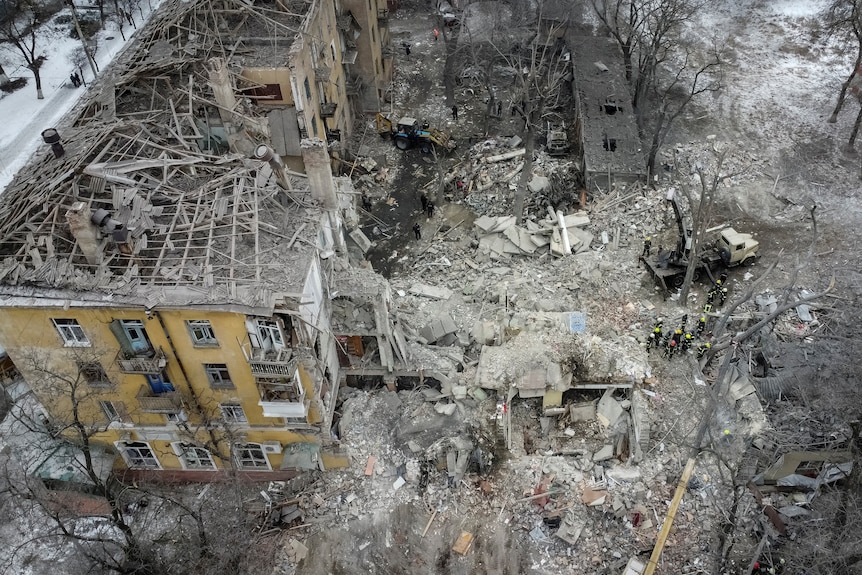 Aerial view of several destroyed residential buildings, with tonnes of rubble and debris on the ground.